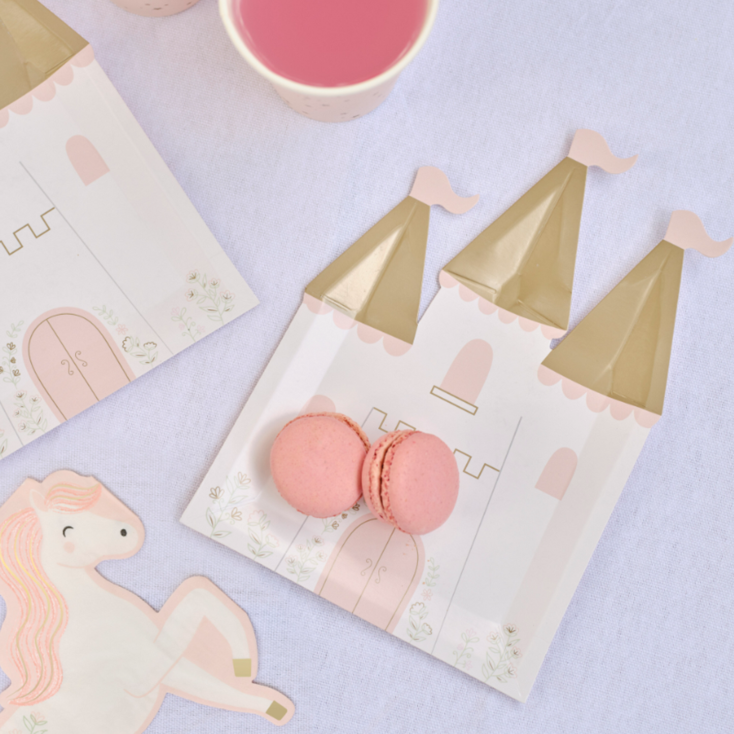 Princess table setting with Castle shape paper plate wih gold towers, pink flags and window, door colours. and fairytale pink and off white horse shape paper napkin.